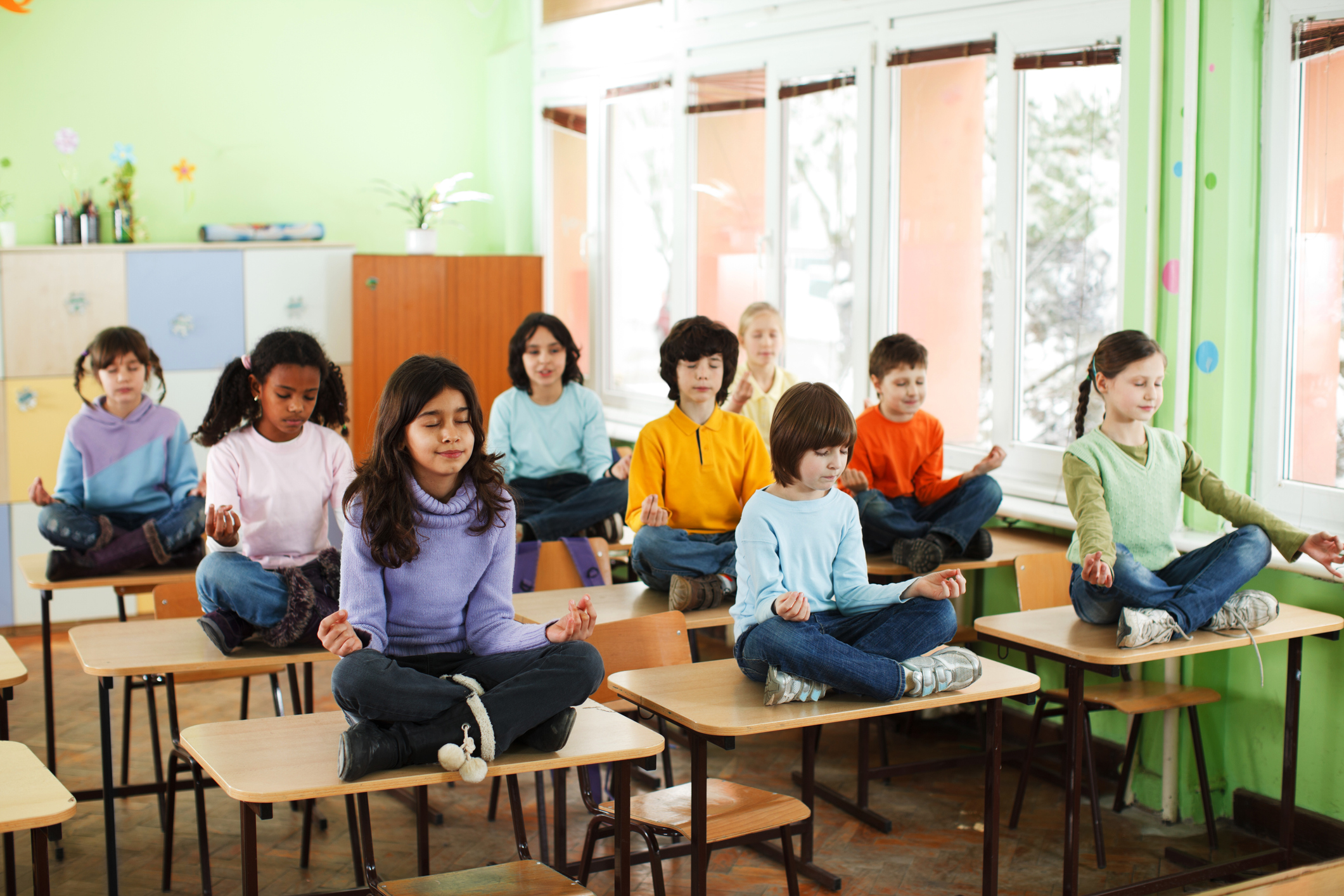 Grupo de alunos pratica meditação em sala de aula. Foto: Getty Images.