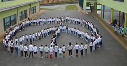 Crianças se reúnem no pátio da escola para formar o símbolo da paz. A atividade foi uma sugestão do projeto 200 Escolas pela Paz e Não-Violência. Foto: Divulgação.