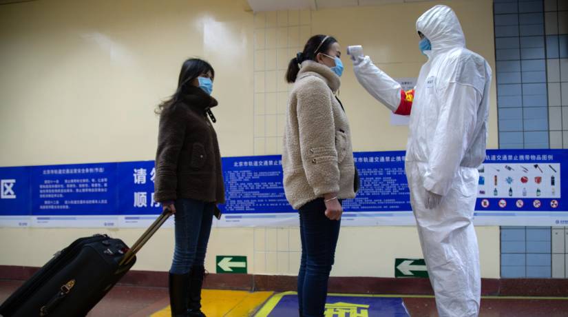 Funcionário mede a temperatura dos passageiros do metrô em Pequim, na China. Foto: Betsy Joles/Getty Images